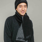 Man standing wearing a black Koru merino and possum NZ Supporters Silver Fern Scarf.