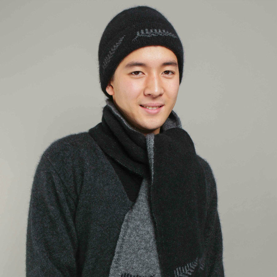 Man standing wearing a black-coloured Koru merino and possum NZ Supporters Silver Fern Beanie.