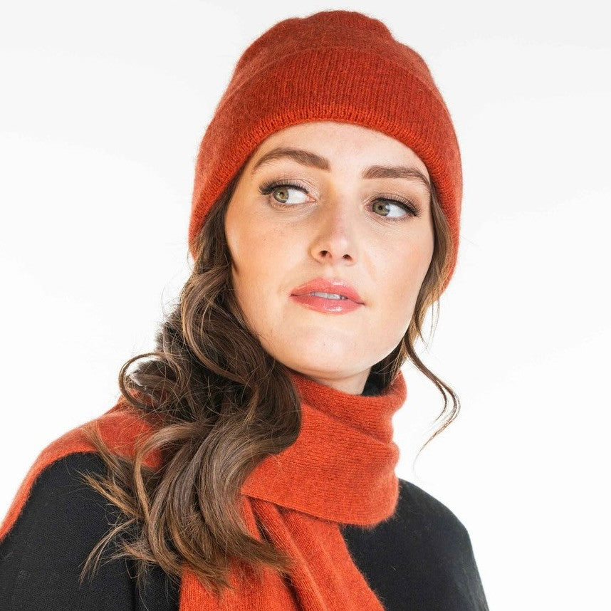 A woman wearing an sienna-coloured Koru Merino and Possum Plain Beanie.