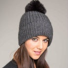 Woman wearing a black and grey coloured Koru merino and possum fur Pom Pom Beanie. Grey/Black