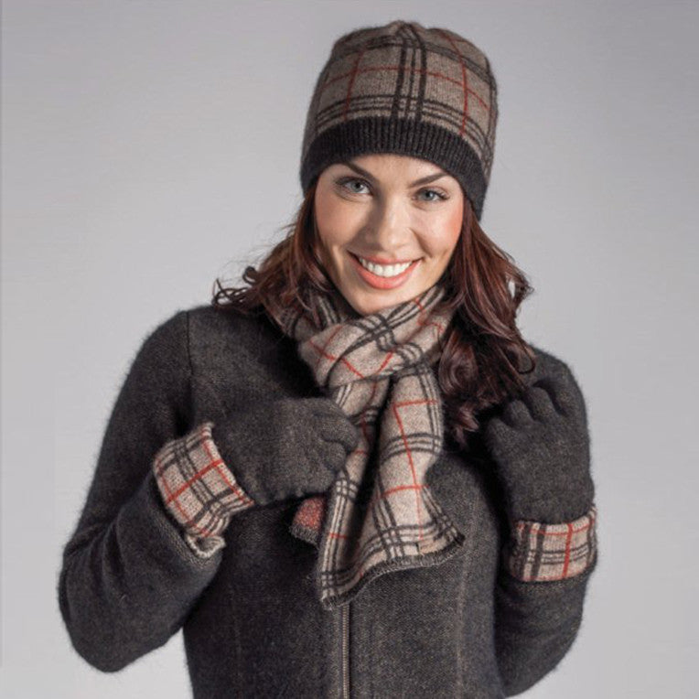 A woman standing wearing a mocha, espresso, and rata-coloured Koru merino and possum Tartan Scarf.