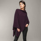 A woman standing wearing a grape-coloured Koru merino and possum Two Way Poncho.