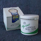 Merino Lanolin Skin Crème with branding on a blanket next to its packaging box.
