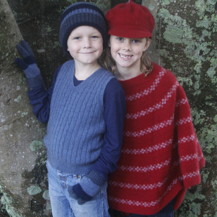 Girl wearing Poncho in colour red, next to boy.