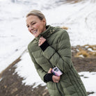 Woman wearing Moke - Sydney Cloud Touch 90/10 Down Coat (SYDNEY) in the colour Olive Green on a hill with snow in the background.