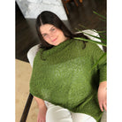 Woman sitting down wearing cotton poncho. Colour Fern