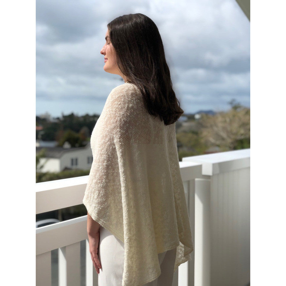 Woman wearing cotton poncho. Colour Cream