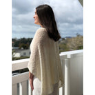 Woman wearing cotton poncho. Colour Cream