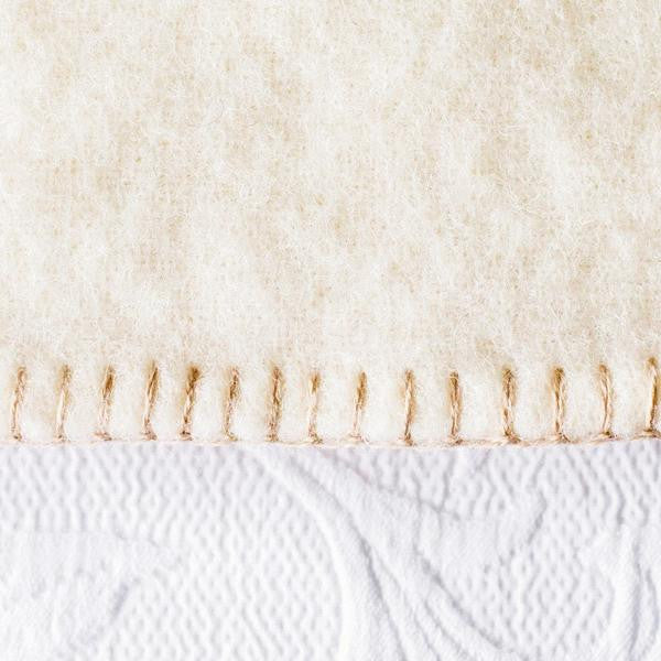 White wool blanket with darker stitching.