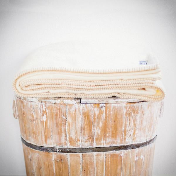 Folded white wool blanket with darker stitching.